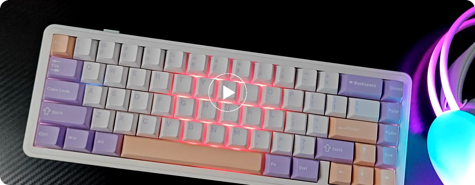 The AULA F65 on a desk at an angle: white case, purple and pink keycaps, RGB lighting on