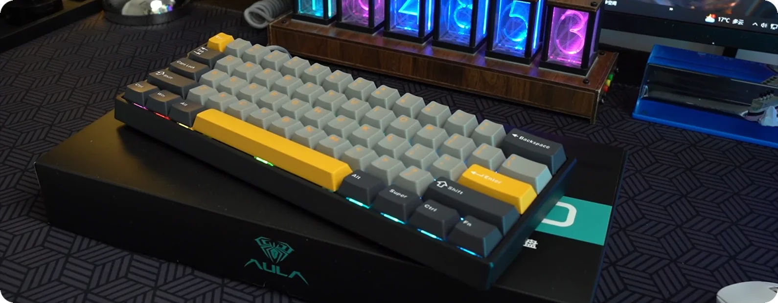 An AULA WIN60 in gray and yellow on a gaming desk, showing the Alt, Super, Ctrl, Fn bottom row and the case edge