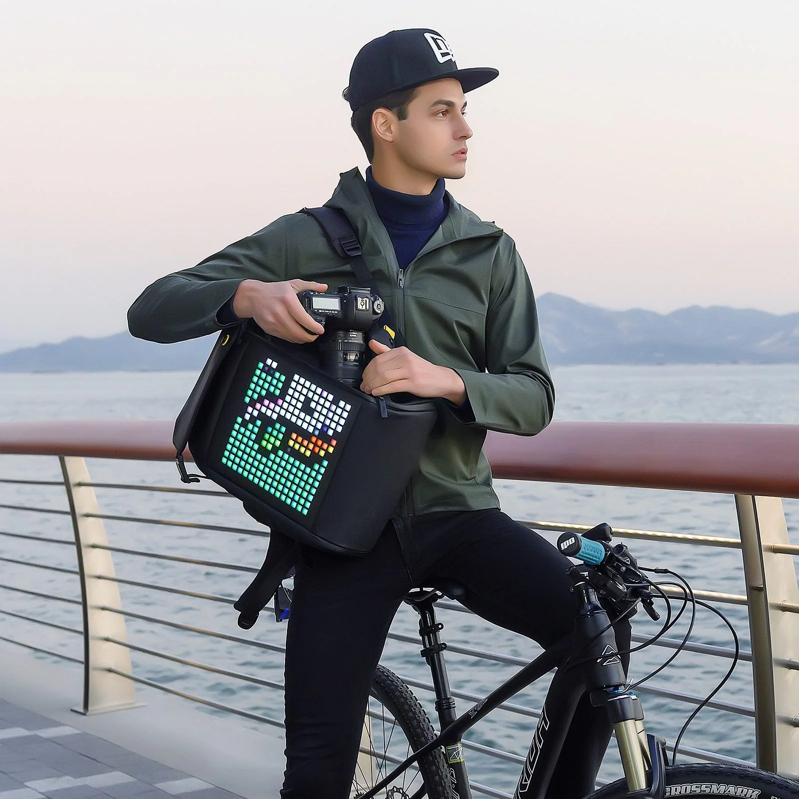 Велосипедист с камерой и рюкзаком Pixoo Backpack-M у набережной, на панели пиксельный персонаж