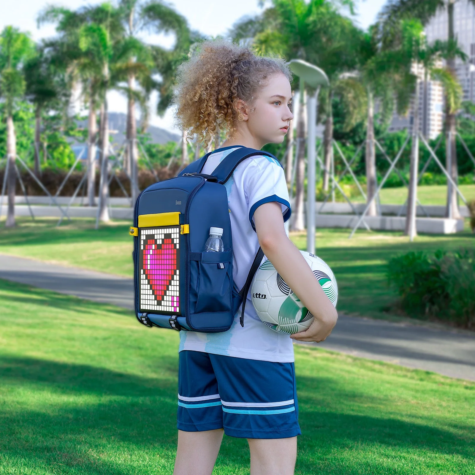 Школьница в парке с синим рюкзаком Divoom Backpack-S, на экране пиксельное сердце
