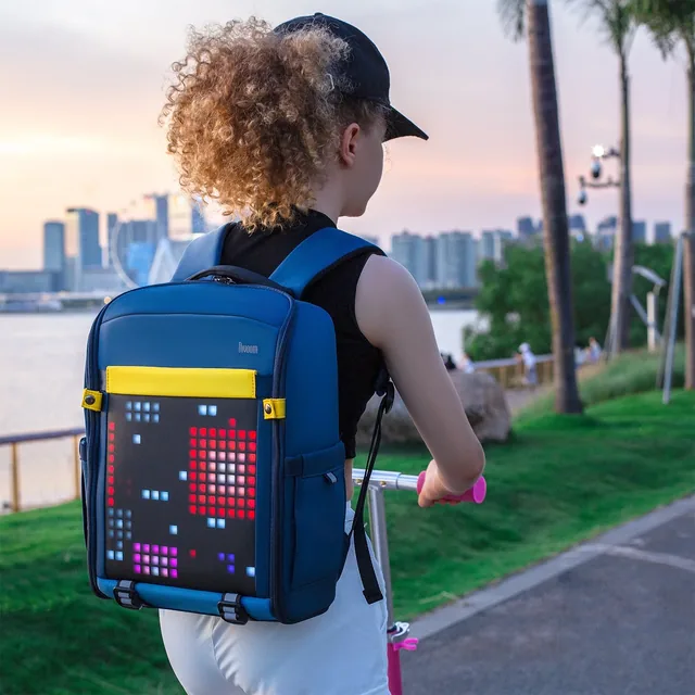 Подросток на самокате у набережной с рюкзаком Divoom Backpack-S, пиксельный рисунок светится в сумерках