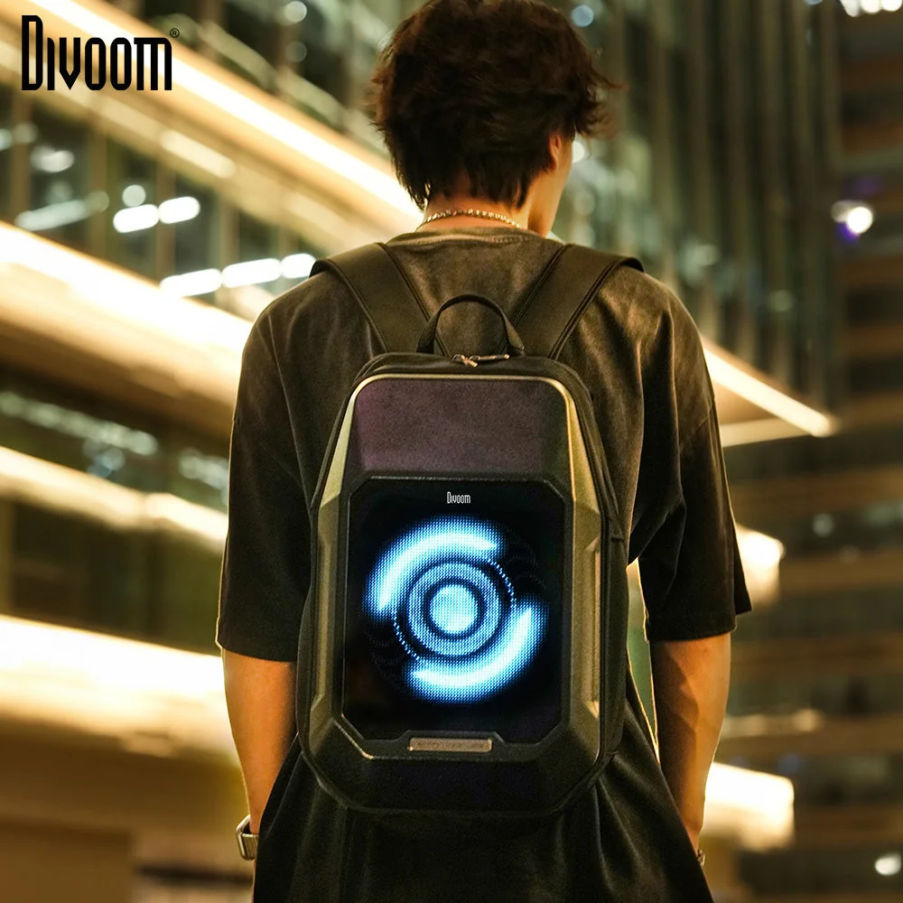 Парень в вечернем городе с чёрным рюкзаком Divoom Cyberbag, на экране синий пиксельный узор