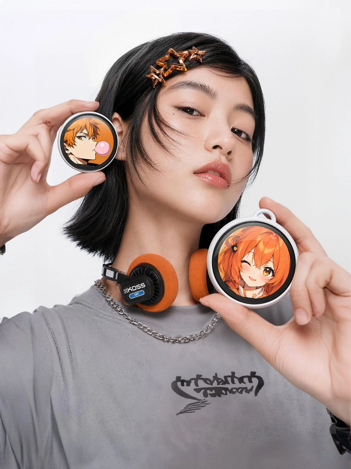 Two Divoom Emodo badges held in hand, showing anime art and their straps
