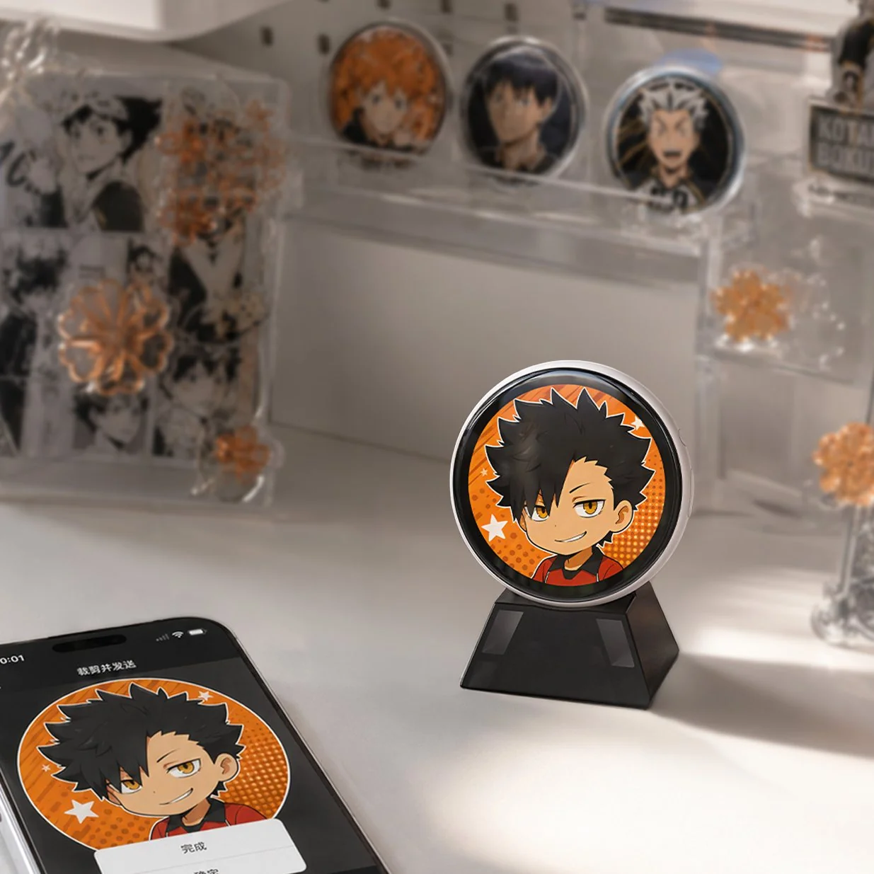 White Divoom Emodo on a display stand among pin badges and merch