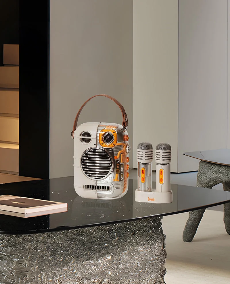 Divoom Spark-Pro and two microphones on a dark glass table in a styled interior